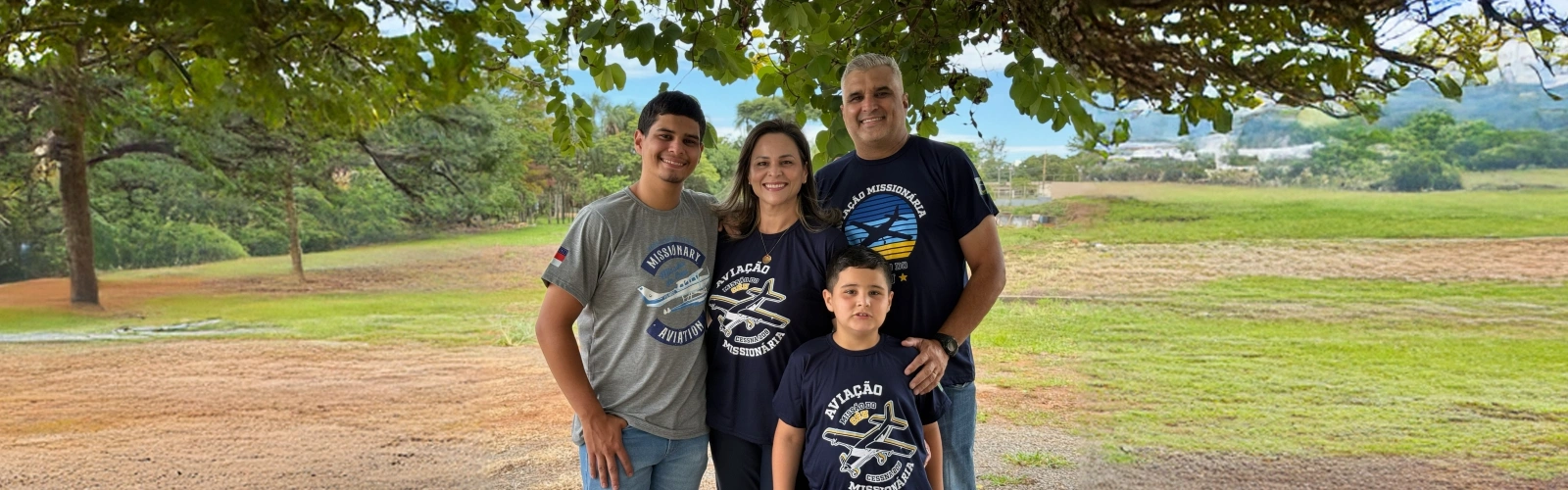 Família Ribeiro em ambiente externo, vestindo camisetas da Aviação Missionária