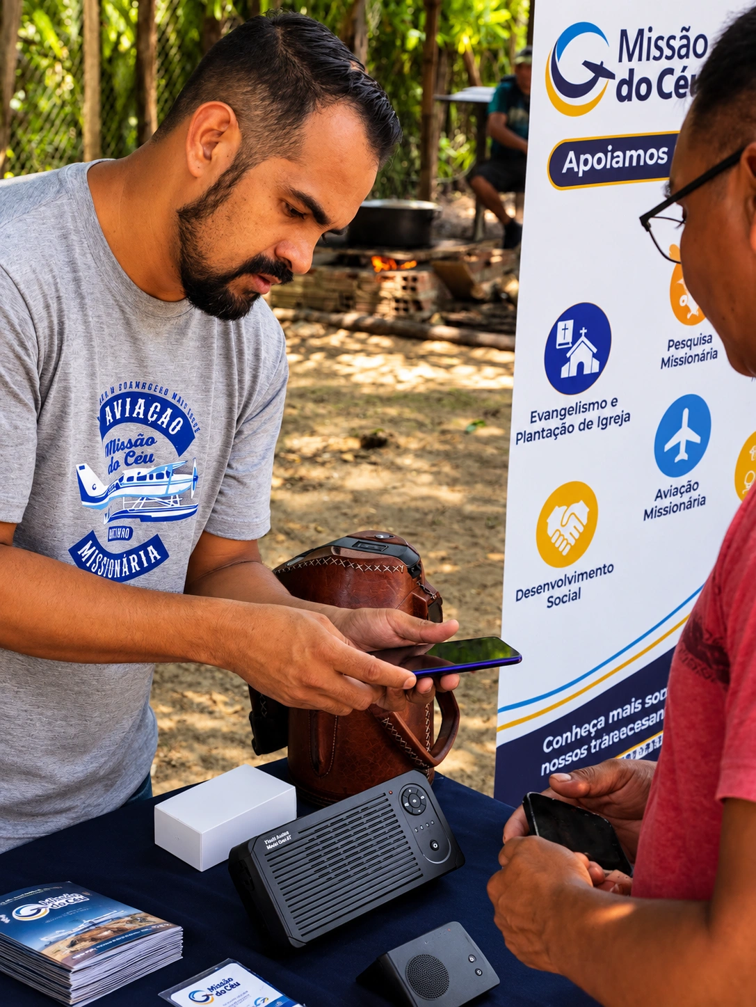 Voluntário apresentando o Proclaimer, rádio a energia solar, em um estande da Missão do Céu